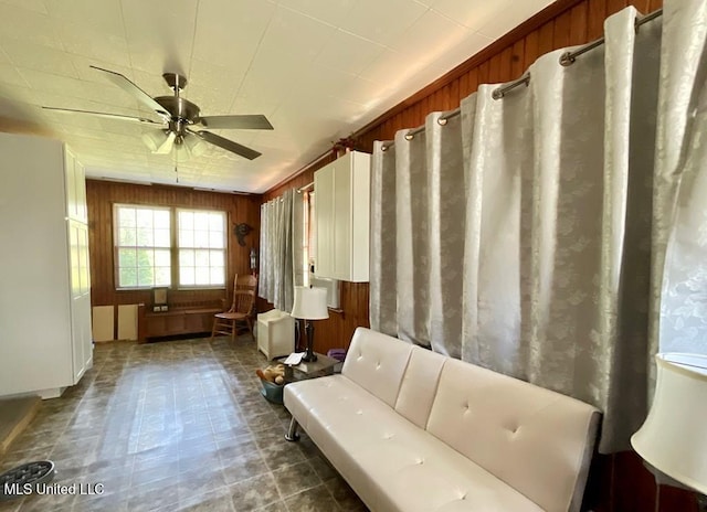 interior space featuring ceiling fan and wood walls