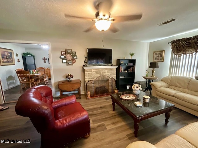 living room featuring a stone fireplace, ceiling fan, and hardwood / wood-style floors