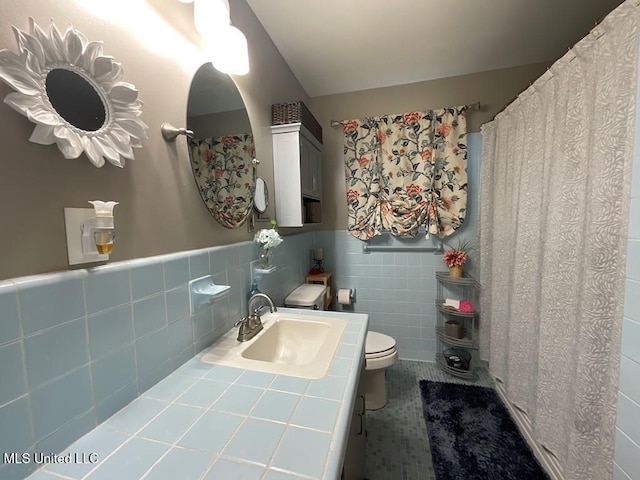 bathroom with vanity, toilet, and tile walls