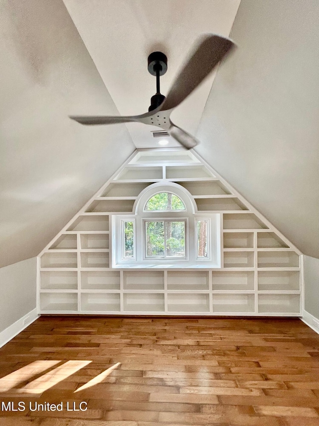 additional living space with baseboards, wood finished floors, lofted ceiling, and built in shelves