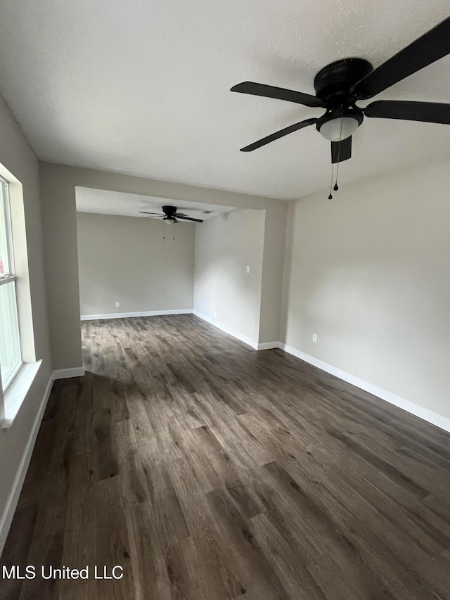 empty room with a textured ceiling, ceiling fan, and dark wood-type flooring