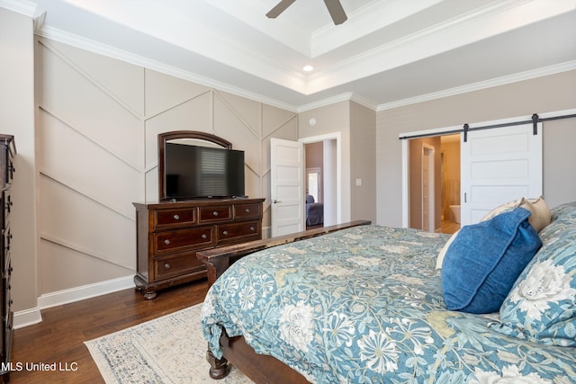 bedroom featuring dark wood-type flooring, ornamental molding, a barn door, a raised ceiling, and ceiling fan