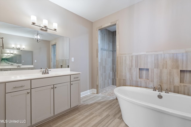 bathroom featuring a freestanding tub, wood finished floors, a tile shower, tile walls, and vanity