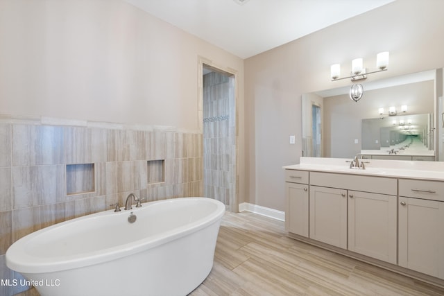 bathroom featuring vanity, wood finished floors, a soaking tub, walk in shower, and tile walls