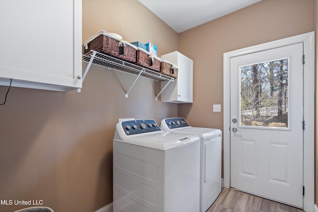 washroom with cabinet space, washing machine and dryer, and light wood-style flooring