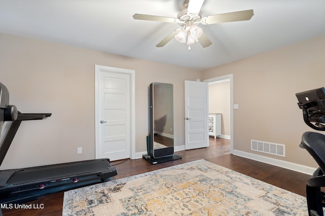 exercise room with visible vents, baseboards, ceiling fan, and dark wood-style flooring