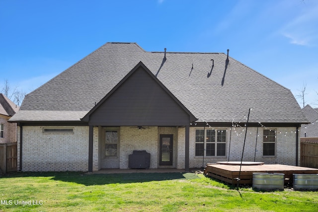 back of house featuring fence, a yard, brick siding, ceiling fan, and a hot tub