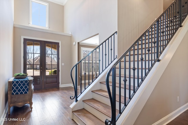 entryway featuring wood finished floors, baseboards, a high ceiling, stairs, and french doors