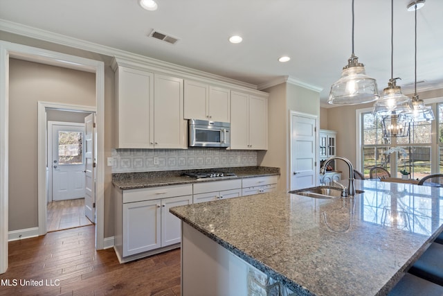 kitchen featuring visible vents, a sink, ornamental molding, appliances with stainless steel finishes, and dark wood-style flooring