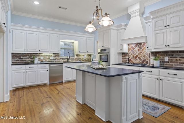 191 N Brandon Blvd, Brandon, MS 39042 - kitchen featuring stainless steel appliances, dark countertops, custom range hood, a kitchen island, and ornamental molding
