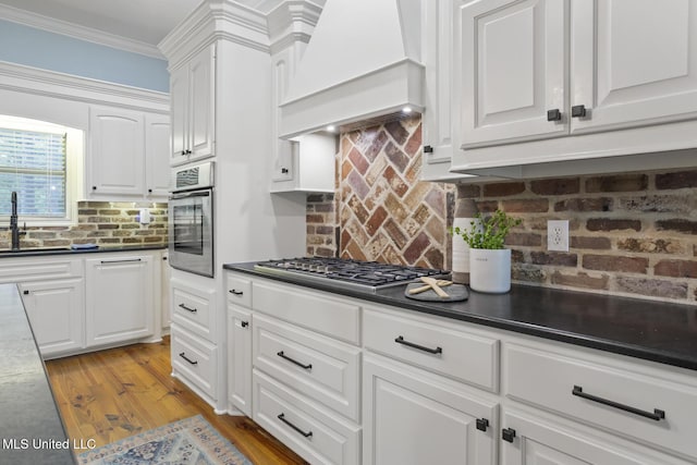 191 N Brandon Blvd, Brandon, MS 39042 - kitchen with appliances with stainless steel finishes, custom range hood, white cabinets, backsplash, and crown molding