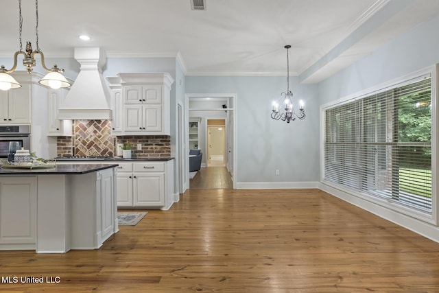191 N Brandon Blvd, Brandon, MS 39042 - kitchen with a chandelier, oven, dark countertops, premium range hood, and white cabinetry