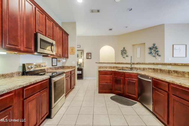 kitchen featuring reddish brown cabinets, visible vents, appliances with stainless steel finishes, a sink, and light tile patterned flooring