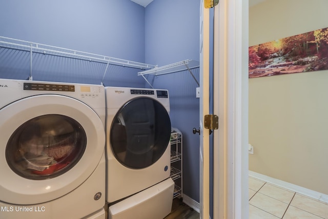 laundry area with laundry area, light tile patterned flooring, washer and clothes dryer, and baseboards