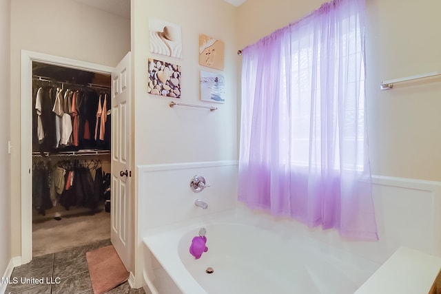 bathroom featuring a healthy amount of sunlight, a walk in closet, and a bath