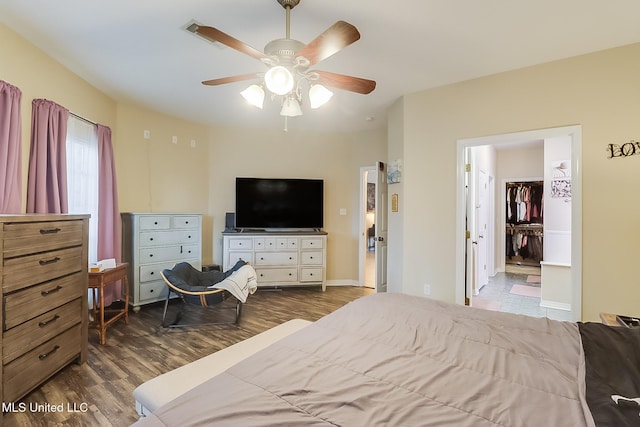 bedroom featuring a spacious closet, dark wood-style flooring, a ceiling fan, and baseboards