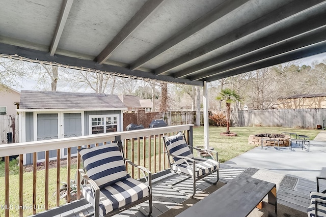 wooden terrace featuring a patio, an outdoor fire pit, a fenced backyard, an outdoor structure, and a yard