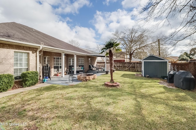 view of yard featuring an outbuilding, a patio, a storage shed, a fenced backyard, and a fire pit