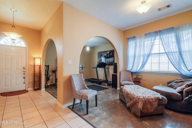 foyer featuring arched walkways, light tile patterned flooring, visible vents, and baseboards