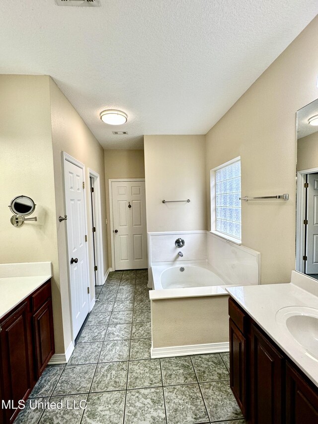 6901 N Rue Mornay, Biloxi, MS 39532 - bathroom with vanity, a bath, a textured ceiling, and tile patterned flooring