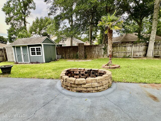 6901 N Rue Mornay, Biloxi, MS 39532 - fenced backyard with an outdoor fire pit, a patio area, and a storage unit