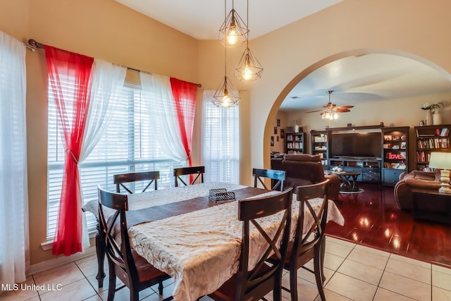 dining area with light tile patterned floors, ceiling fan, and arched walkways