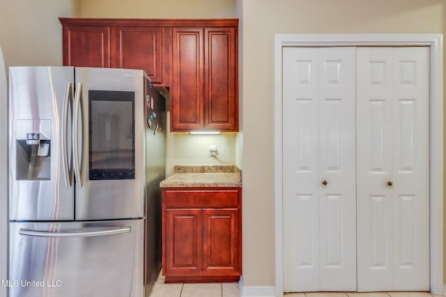 kitchen featuring light tile patterned floors, stainless steel fridge, and dark brown cabinets