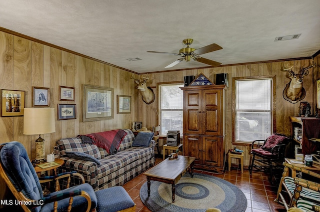 living room featuring wooden walls, ceiling fan, a textured ceiling, and dark tile patterned flooring