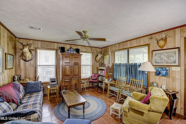 living room featuring ornamental molding, wood walls, tile patterned flooring, and ceiling fan