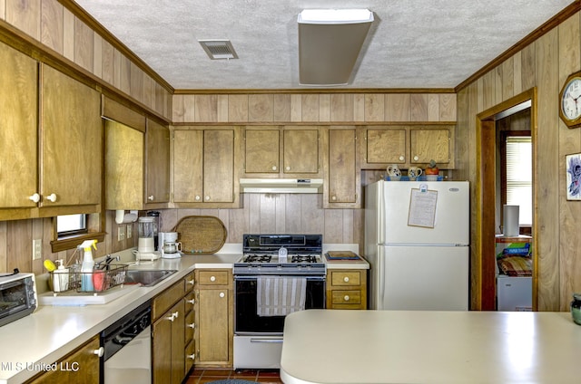 kitchen with a textured ceiling, ornamental molding, wood walls, sink, and white appliances