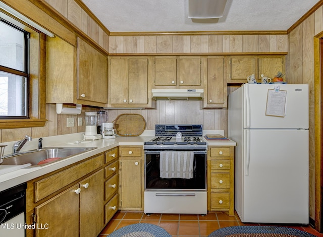 kitchen featuring a textured ceiling, wood walls, light tile patterned flooring, sink, and white appliances