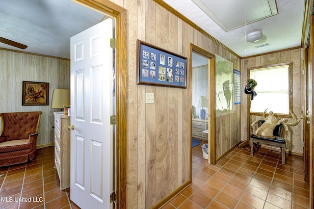 corridor with tile patterned floors, wooden walls, and ornamental molding