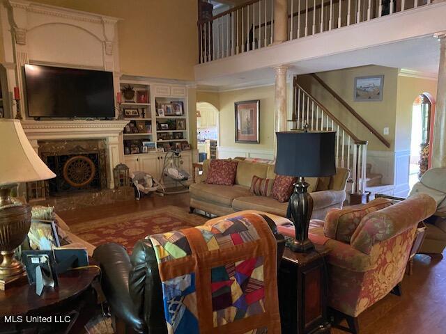 living room featuring crown molding, a towering ceiling, and wood-type flooring