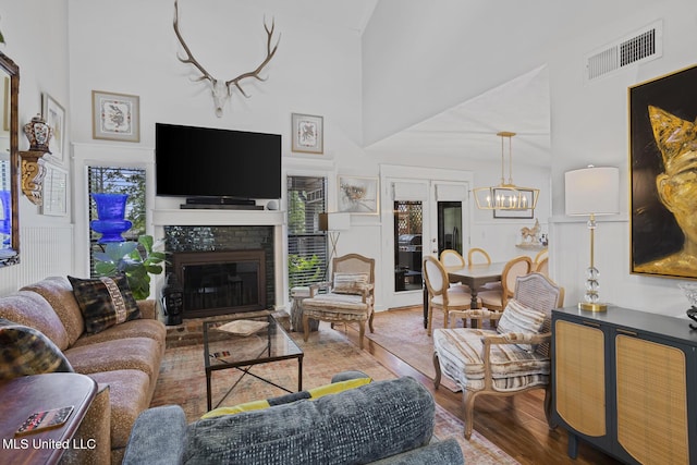 821 Planters Point Dr, Canton, MS 39046 - living area featuring wood finished floors, high vaulted ceiling, a chandelier, and a glass covered fireplace