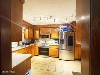 101 Dogwood Cir, Brandon, MS 39047 - kitchen with stainless steel appliances, light countertops, brown cabinetry, light tile patterned flooring, and decorative backsplash