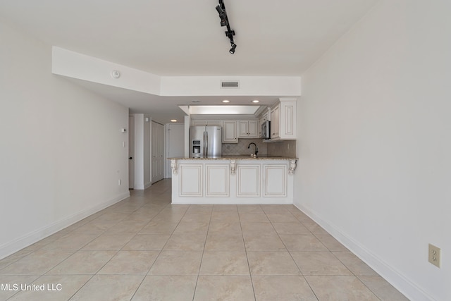 kitchen with kitchen peninsula, white cabinets, stainless steel appliances, and light stone counters