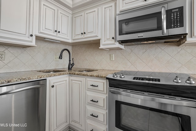 kitchen with light stone countertops, sink, stainless steel appliances, white cabinets, and decorative backsplash