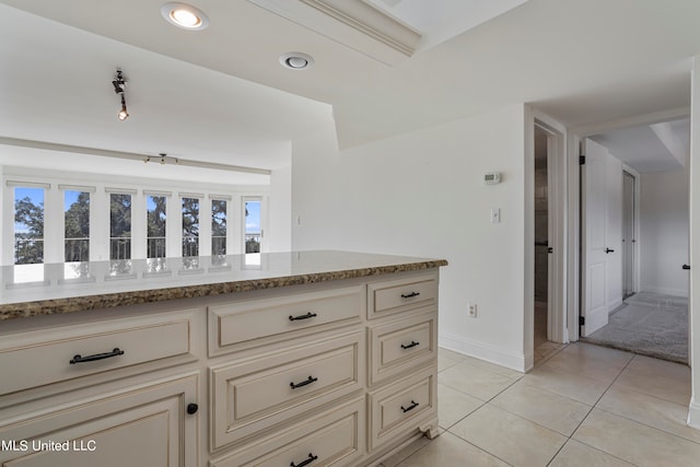 kitchen featuring cream cabinets, light stone counters, and light tile patterned floors