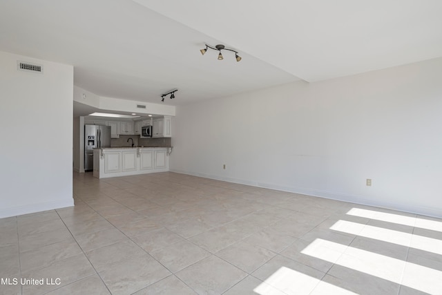 unfurnished living room featuring sink and light tile patterned flooring