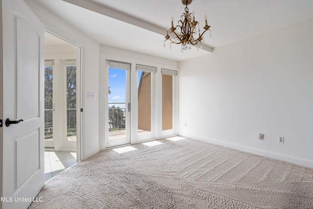 carpeted spare room featuring a chandelier and a wealth of natural light