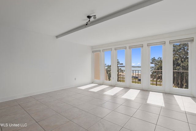 tiled empty room with beam ceiling and a water view