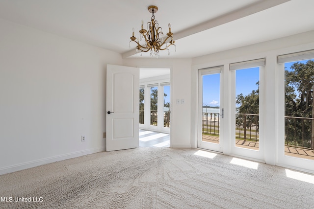 carpeted spare room featuring an inviting chandelier