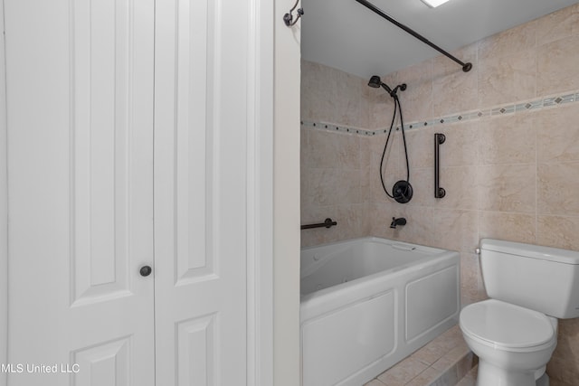 bathroom featuring toilet, tiled shower / bath combo, tile patterned flooring, and tile walls