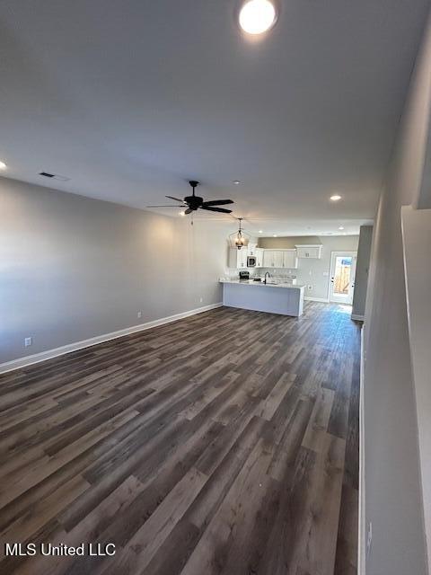 unfurnished living room featuring ceiling fan and dark hardwood / wood-style flooring