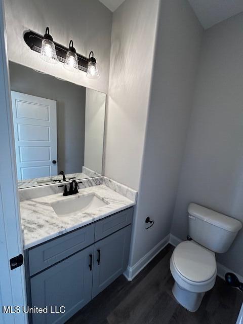 bathroom with hardwood / wood-style floors, toilet, and vanity