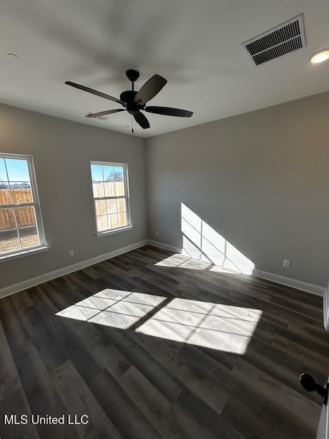 empty room with ceiling fan and dark hardwood / wood-style flooring