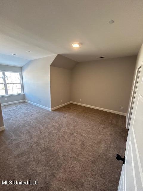 carpeted empty room featuring vaulted ceiling