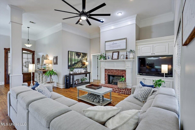 living room with crown molding, a brick fireplace, hardwood / wood-style floors, and ceiling fan