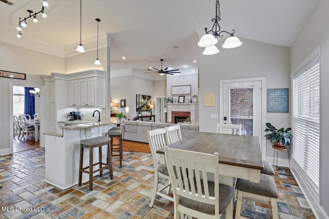 dining space with high vaulted ceiling, a healthy amount of sunlight, and a fireplace