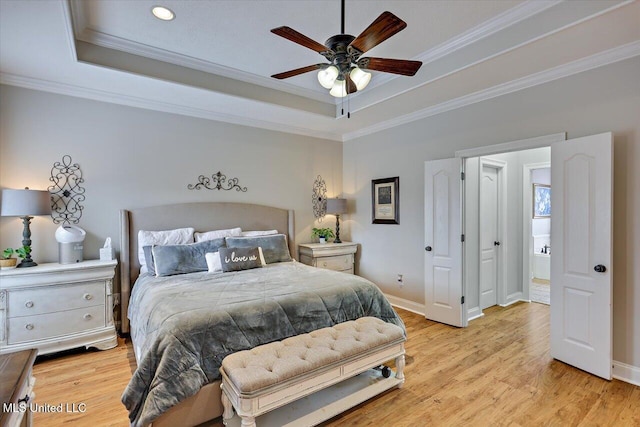 bedroom featuring crown molding, a tray ceiling, light hardwood / wood-style flooring, and ceiling fan